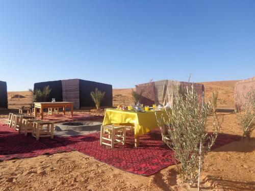 a yellow table in the middle of the desert at Camel Trek Bivouac in Merzouga