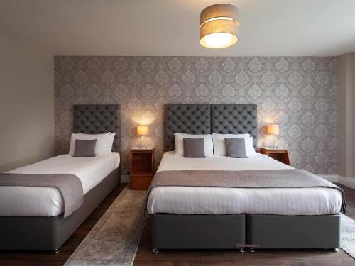 two beds in a hotel room with two lamps at Elfordleigh Hotel in Plymouth
