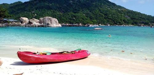 a red boat sitting on a beach next to the water at Nangyuan Island Dive Resort in Koh Tao
