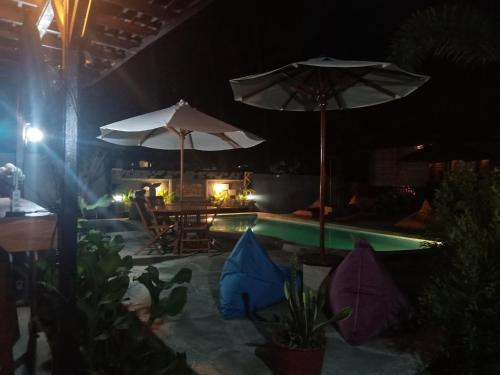a pool with two umbrellas and a table and chairs at ZiFa Mandalika in Kuta Lombok
