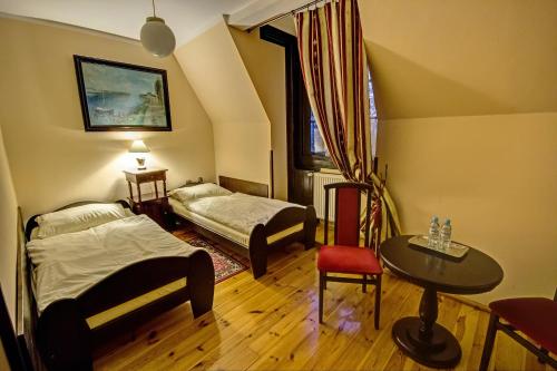 コンティ・ブロツワフスキエにあるPałac Krobielowiceのベッド2台、テーブル、椅子が備わる客室です。
