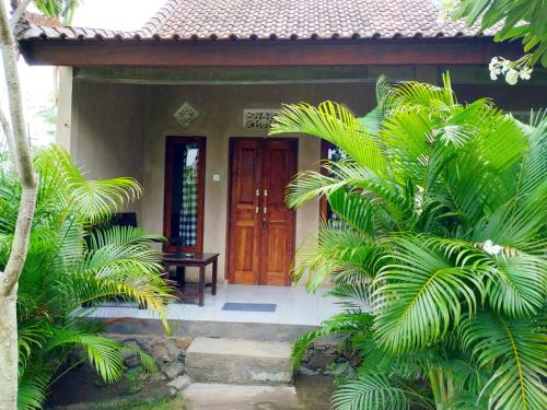 ein Haus mit einer Holztür und einigen Palmen in der Unterkunft Angga Guest House in Pemuteran
