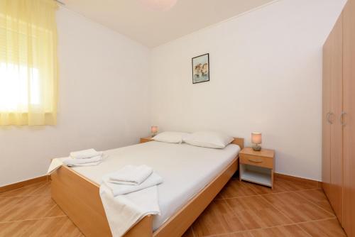 a white bedroom with a bed with towels on it at Apartmani Petra in Trogir