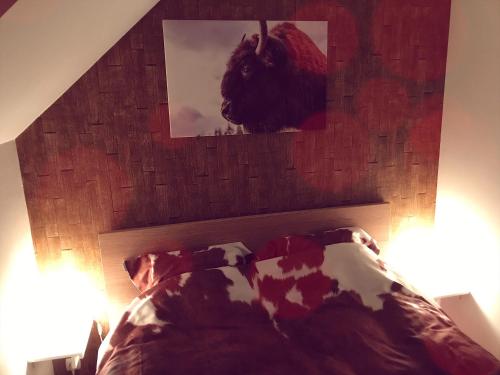 a bedroom with a headboard with a picture above a bed at Villa Dakota - jacuzzi, zwembad, playstation in Durbuy
