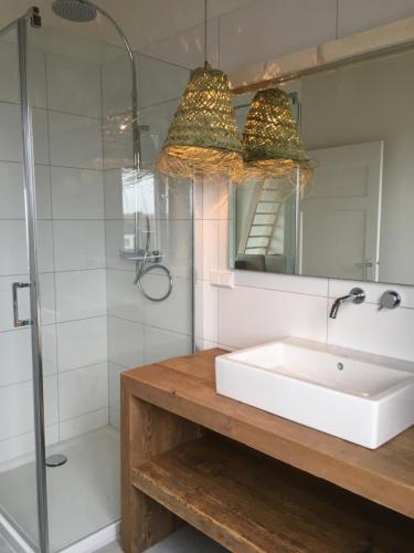 a bathroom with a sink and a shower and a mirror at Eb en Vloed Katwijk in Katwijk
