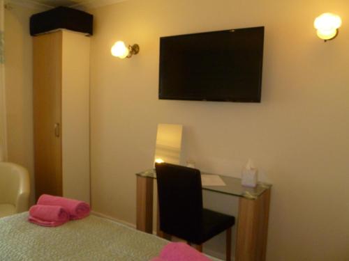a hotel room with a desk and a television on the wall at Greenlaw Guest House in Gretna Green