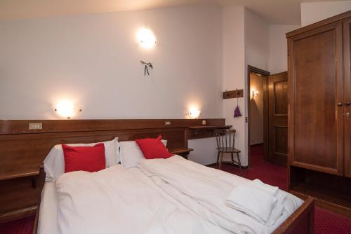 a bedroom with a large white bed with red pillows at Locanda ai Dogi in Pieve di Cadore
