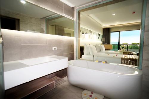 Pattaya Discovery Beach Hotel - SHA Extra Plus في باتايا سنترال: حمام مع حوض ومرآة كبيرة