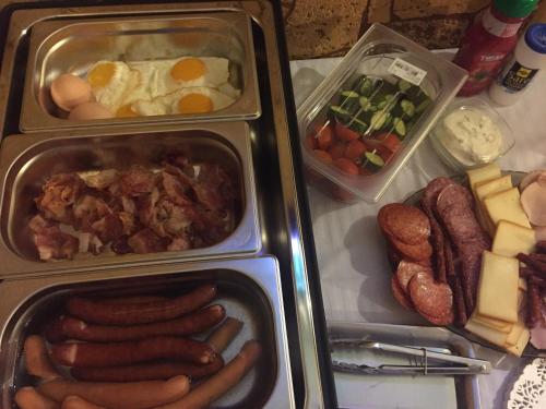 two trays of food with sausage eggs and other foods at Oli House in Alba Iulia