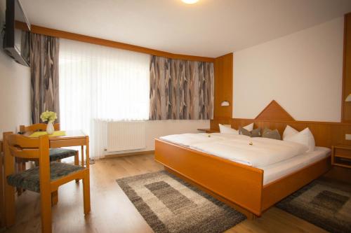 a bedroom with a large bed and a desk and a window at Haus Enzian in Sankt Leonhard im Pitztal