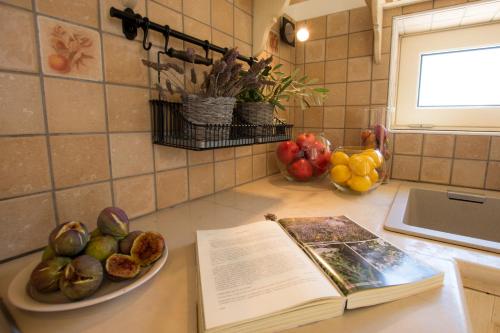 a book on a kitchen counter with fruits and vegetables at Le Gioie - Villa Macchia Mediterranea - Splendida villa vista mare immersa nel verde in Torre Pali 