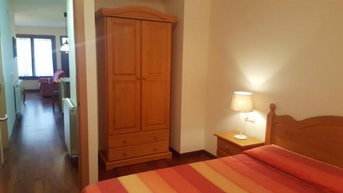 a bedroom with a bed and a cabinet and a lamp at Can Marxant, céntrico, servicios al lado y cruce de senderos in Molló