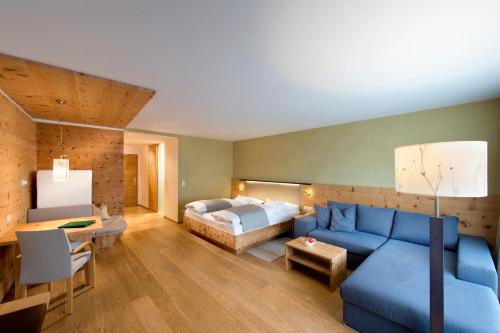 a living room with a blue couch and a bed at Naturhotel Leitlhof in San Candido