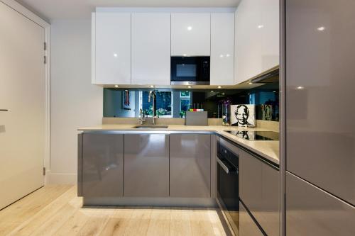 a kitchen with white cabinets and a stainless steel refrigerator at Sleek Arty Apartment in London