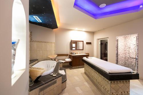 La salle de bains est pourvue d'une grande baignoire, d'un lavabo et d'une baignoire. dans l'établissement Mediterranee Family & Spa Hotel, à Bibione