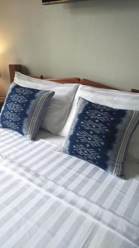 a bed with blue and white pillows on it at Sean Sabai Home e Ristobar in Taling Ngam Beach
