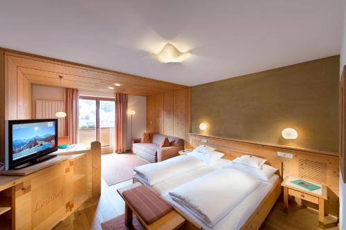 a bedroom with a large bed and a television at Naturhotel Leitlhof in San Candido