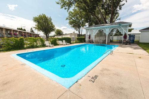 a swimming pool with a gazebo in a yard at Auberge le Parasol in Saguenay