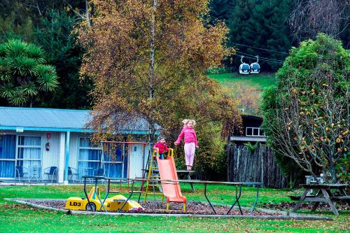 two children playing on a playground in a yard at Fairy Springs Motel in Rotorua