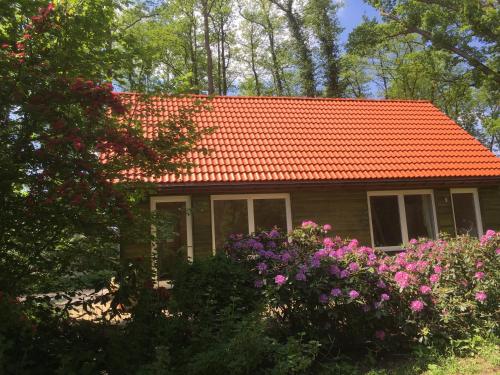 ein kleines Haus mit orangefarbenem Dach und ein paar Blumen in der Unterkunft Ferienhof Ohlenbusch in Worpswede