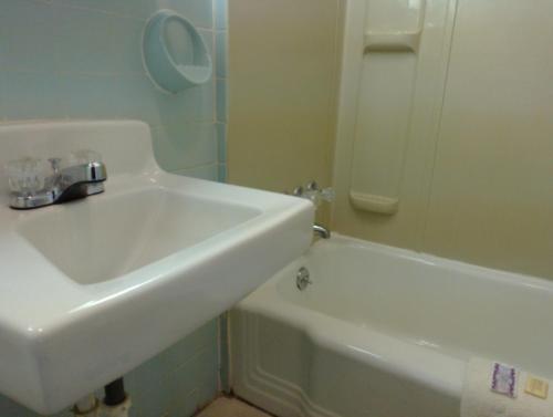 a bathroom with a sink and a bath tub at Colonial Inn Mercer-Grove City in Mercer