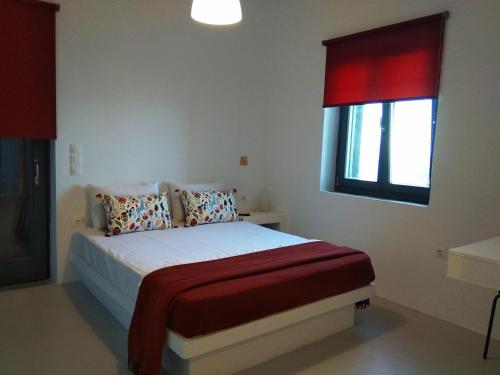 a bedroom with a bed with a red window at Calme et détente. Vue panoramique mer Égée. in Spathi 