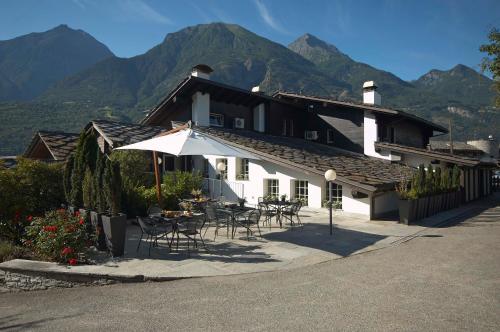 a building with a table and chairs and an umbrella at Hotel Village in Aosta