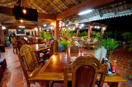 a restaurant with wooden tables and chairs and a television at Okay Guesthouse Siem Reap in Siem Reap