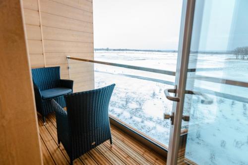 a balcony with two chairs and a sliding glass door at Jurmala Golf Club&Hotel in Piņķi