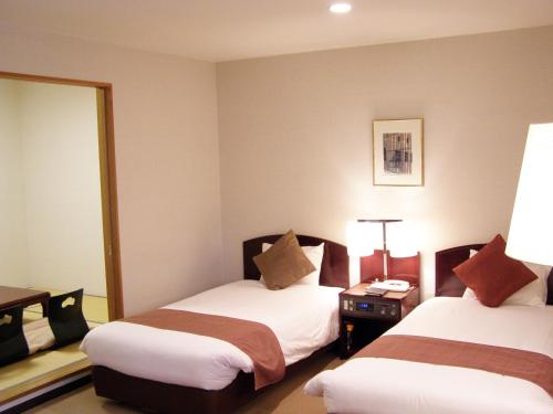a hotel room with two beds and a mirror at Hotel Marroad Karuizawa in Karuizawa
