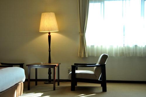a hotel room with a bed and a chair and a lamp at Hotel Marroad Karuizawa in Karuizawa