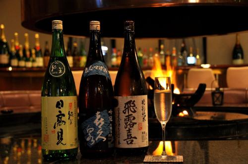 three bottles of wine sitting on a bar with a glass at Hotel Marroad Karuizawa in Karuizawa