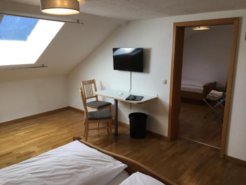 a bedroom with a bed and a desk and a tv at Hotel im Sonnental in Jachenau