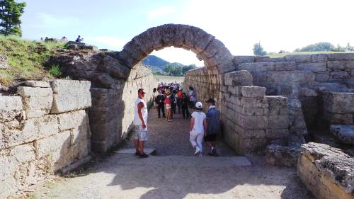a group of people walking through a stone archway at Villa Finiki Messinia upstairs in Foiníki