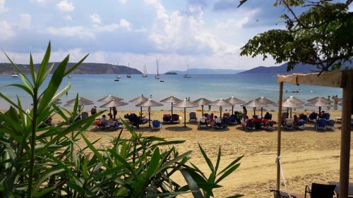 a beach with umbrellas and people sitting on the sand at Villa Finiki Messinia upstairs in Foiníki