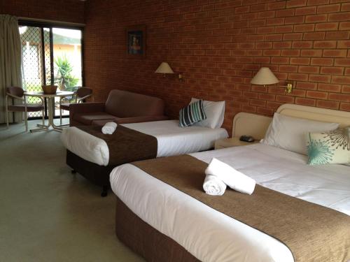 a hotel room with two beds and a brick wall at Ashleigh Court Motor Inn in Mulwala