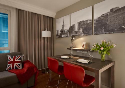 a dining room with a table and red chairs at Citadines Trafalgar Square in London