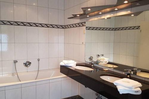 a bathroom with two sinks and a tub and a mirror at Zimmervermietung Mülheim in Mülheim an der Ruhr
