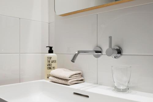 a white bathroom sink with a soap dispenser and towels at Haus-Ascot-Zermatt in Zermatt