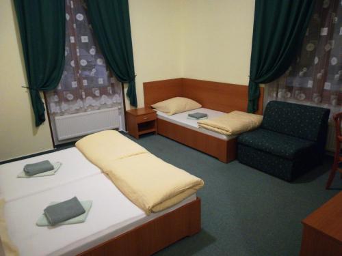 a small room with two beds and a chair at Penzión Rodina in Levoča
