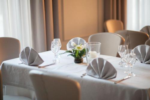 a table with glasses and a vase of flowers on it at Hotel Dei Fiori Restaurant - Meeting & Spa in Alassio