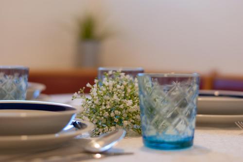 a table with two glasses and a bowl of flowers at Haus Kuen in Merano