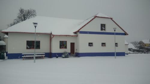 a white building with blue trim on a snow covered field at Čechův dvůr in Louka