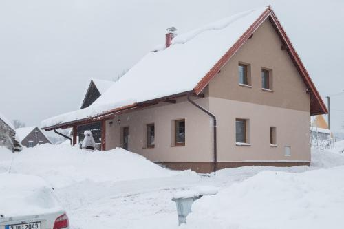 a house covered in snow with a car in front at Chalupa Kadov in Sněžné