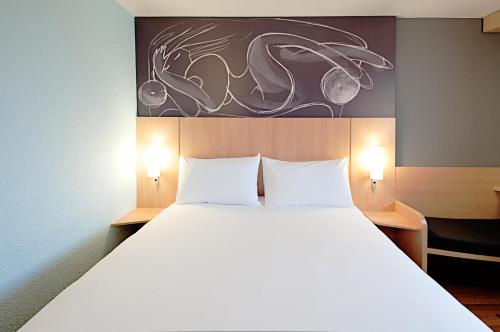 a bedroom with a large white bed with two lamps at Ibis Cornella in Cornellà de Llobregat