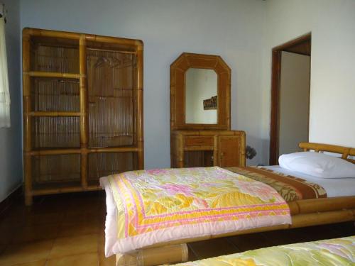Schlafzimmer mit einem Bett, einer Kommode und einem Spiegel in der Unterkunft Pondok Kecil Bungalow in Ubud