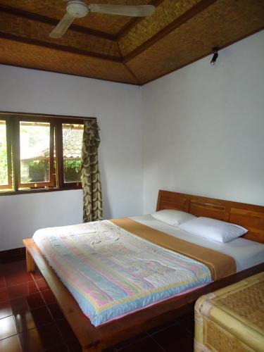 a bedroom with a bed and two windows at Pondok Kecil Bungalow in Ubud