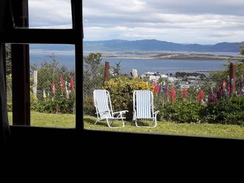 two chairs sitting in the grass looking out a window at Ushuaia Lodge in Ushuaia