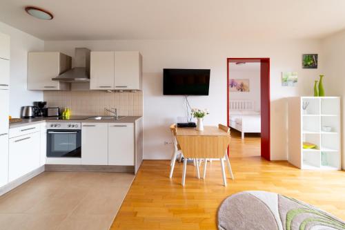 uma cozinha com armários brancos, uma mesa e uma sala de jantar em A Twist of Lime em Moravske-Toplice