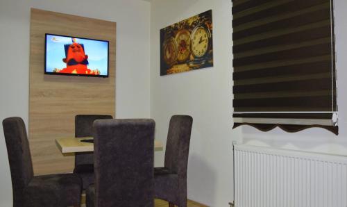 a dining room with a table and a tv on a wall at Apartmani Marić in Novi Pazar